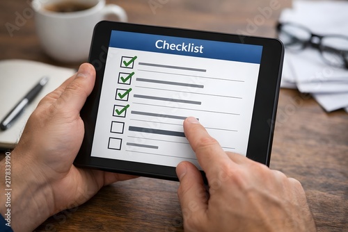 Person checking off tasks on a digital checklist on a tablet computer