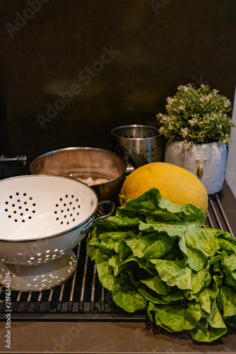 Fresh green lettuce leaves, melon, and vintage colander for Mediterranean meal prep