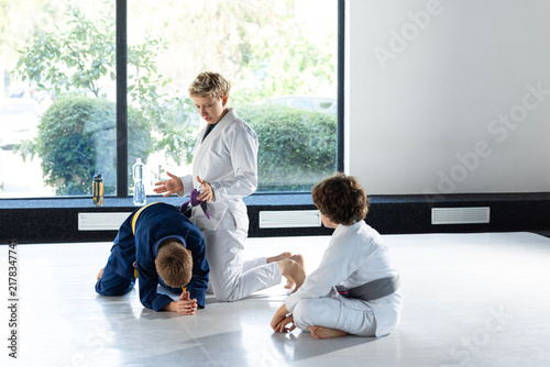 Canvastavla Female coach supervises children learning judo groundwork on training mat