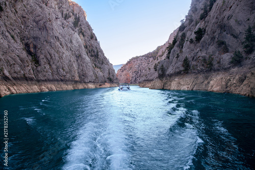 Tour boat cruising through Green Canyon, Turkey, between towering limestone cliffs