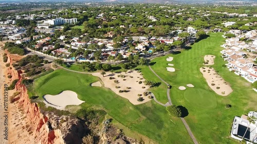 Drone footage flying over the stunning vale do lobo golf course situated on dramatic red cliffs, revealing the beautiful sandy beach and the atlantic ocean in the algarve region of portugal
