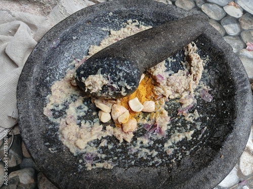 Fotografie Freshly ground herbs and spices in a traditional stone mortar and pestle (cobek