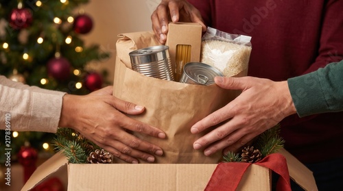 Christmas food drive volunteers pack grocery donation bags while sorting supplies. The team’s holiday work shows shared care, charity, and community support