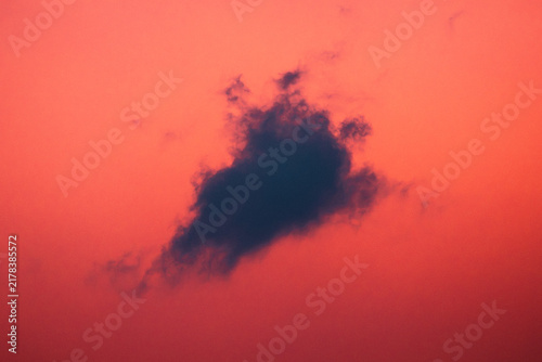 Foto Nuage sombre isolé dans un ciel rouge au coucher du soleil
