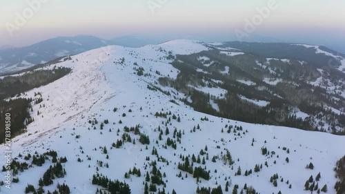 An extraordinary valley with hills and mountains covered with fir forests against the backdrop of a bright pink sunset
