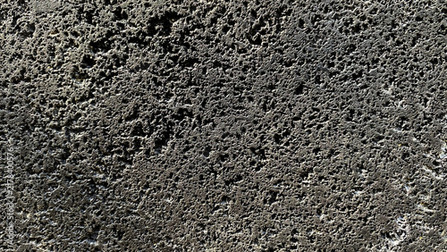 Obraz na plátně Dark grey heavily pitted volcanic stone texture surface background
