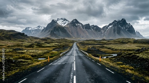 Long straight road leading to dramatic snow capped mountains in Iceland