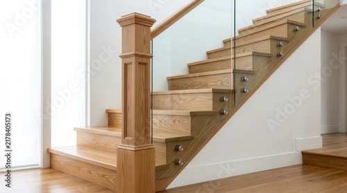 Wooden treads and transparent glass railing with steel frames on stairs with a solid newel post