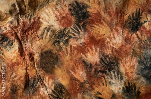 Ancient cave walls adorned with ochre handprints and abstract patterns