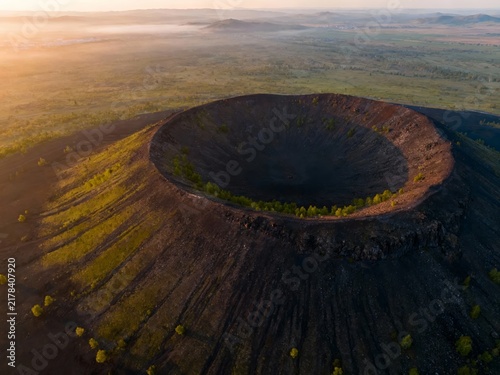 Aerial view of a volcanic crater at sunrise with surrounding landscape