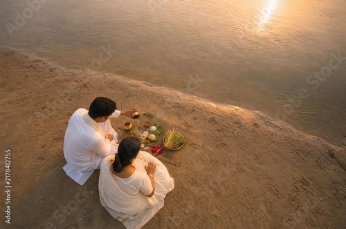 Indian couple performing traditional pitru paksha ritual by river bank