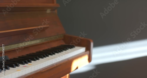 Window sunbeam is shifting on wall while camera is shifting focus across piano keyboard with dots