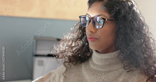 Hearing voice at office, African American woman adjusting glasses and turtleneck, reading monitor