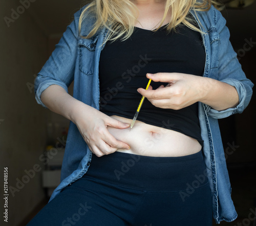 Woman making hormone injection into belly at home for ivf fertility treatment and ovulation stimulation. Concept of reproductive medicine, hormone therapy, and subcutaneous injection.