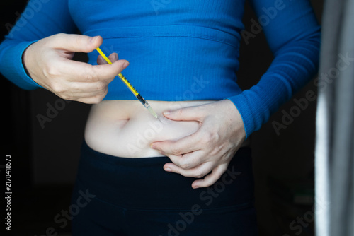 Woman making hormone injection into belly at home for ivf fertility treatment and ovulation stimulation. Concept of reproductive medicine, hormone therapy, and subcutaneous injection.