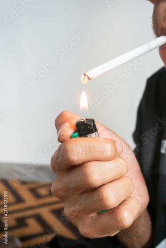 Foto Someone is lighting the tip of a cigarette with a lit green lighter