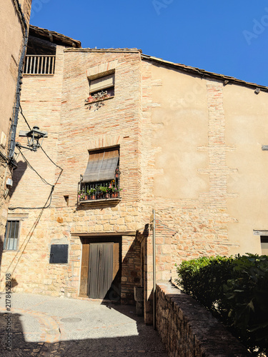 Фотография Brick and stone house with a street lamp on a corner in Alquezar Spain