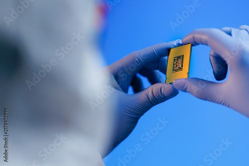 Photography Technician holding microprocessor chip inspecting in laboratory