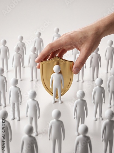 A human hand placing a golden shield in front of a white 3d figure among others with shield protecting single white character standing standing crowd identical holds gold shield