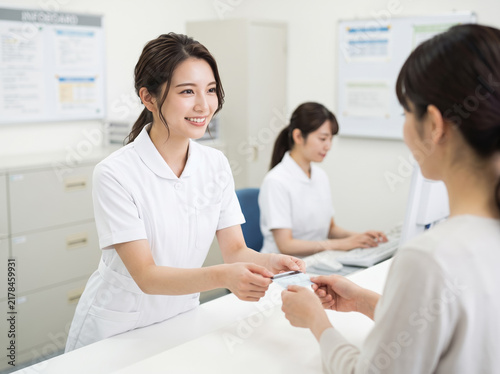 Plakat 病院の受付で笑顔で診察券を手渡す女性