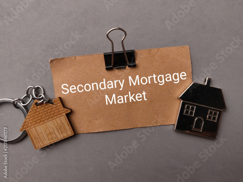 Konstfotografi A binder clip holds a brown note titled Secondary Mortgage Market between two mi