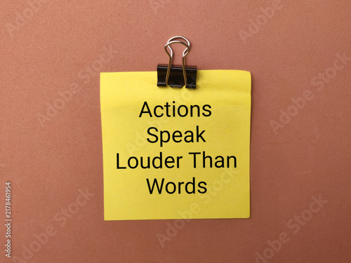 Foto A binder clip secures a yellow note reading Actions Speak Louder Than Words on a