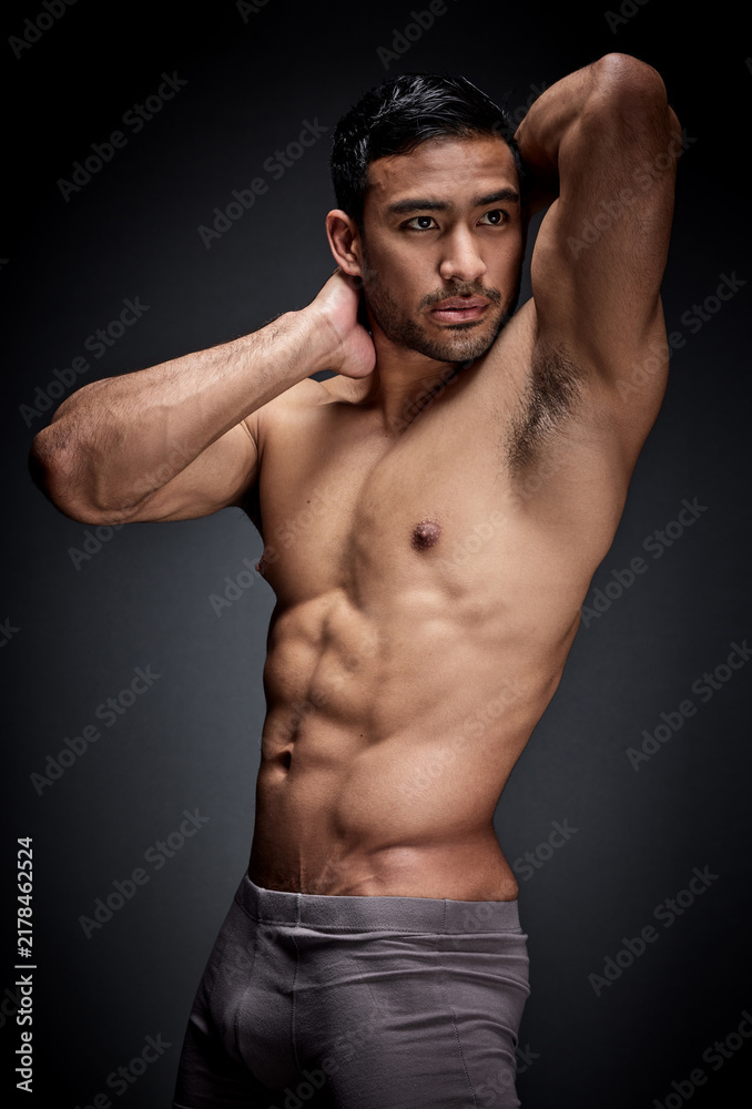 Obraz premium Fitness, asian man and body builder flexing abs and strong chest in sexy underwear for exercise in studio. Health, sport and male person with seductive stomach muscles for training on dark background
