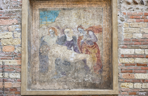 Weathered religious fresco depicting the Virgin Mary mourning Christ in Verona, Italy