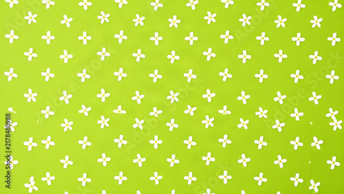 A repeating pattern of small white cross-shaped flowers on a green background.