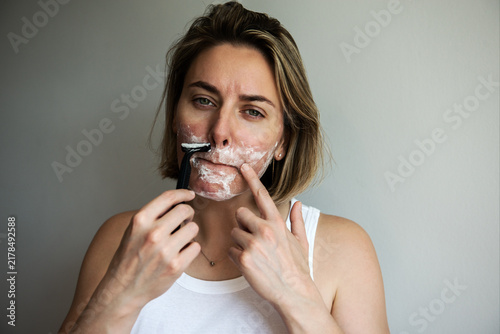 Woman applying facial shaving routine with razor and foam. Beauty, fashion and self-care portrait exploring gender equality, inclusivity, modern grooming habits and contemporary beauty standards