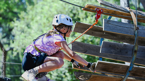 Girl navigating wooden steps on an outdoor adventure park ropes course