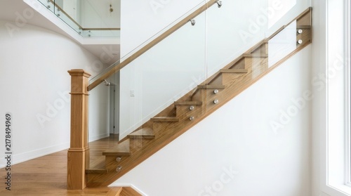 Transparent glass railing held by steel frames and wooden treads on stairs with a solid newel post