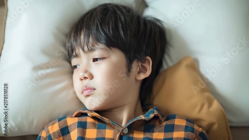 憂鬱そうな表情でベッドに寝転がる男の子