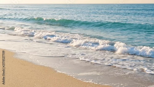 Gentle ocean waves washing onto the sandy beach shoreline with white foam and clear blue water horizon with shore under clear video gentle relaxation background coastline