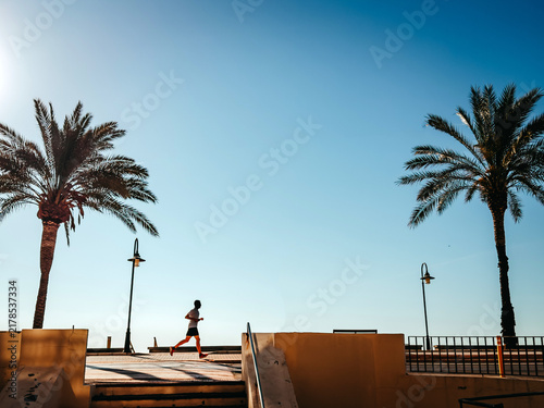 Alone runner on a summer seaside promenade