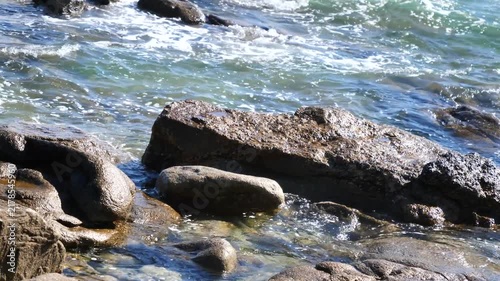 ocean waves crashing on rocky shoreline in bright sunlight