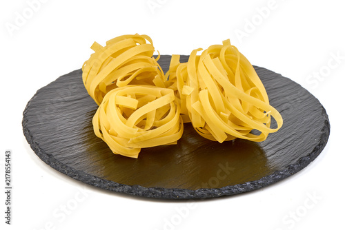 Quadro su tela Uncooked Tagliatelle Pasta Nests on a Dark Slate Plate