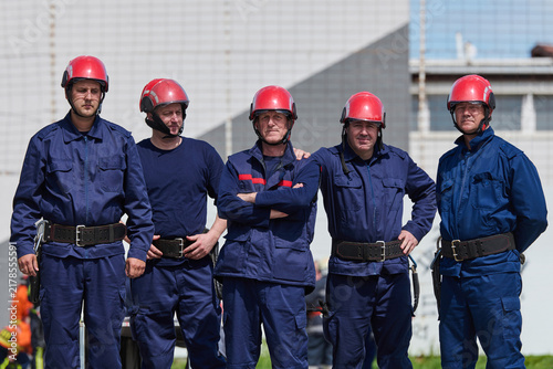 Firefighters Team In Blue Uniforms With Red Helmets Standing Together Ready For Rescue