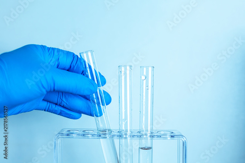 Gloved laboratory technician holding a glass test tube for scientific sample analysis.