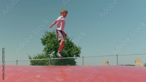 A boy is jumping on a trampoline outdoors
