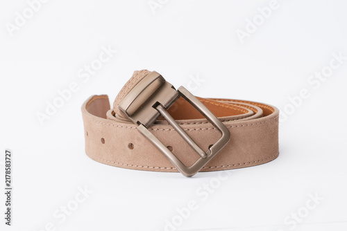 Beige suede leather belt coiled with a bronze metal buckle on a white background