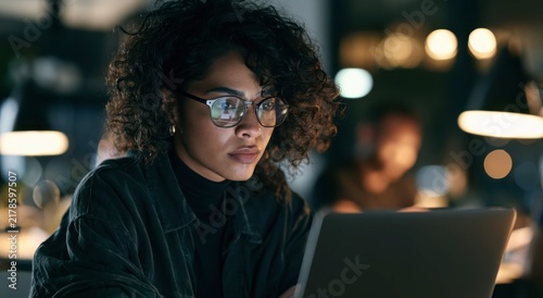 Professional woman using a laptop for secure biometric login in a modern office at night