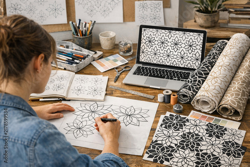 A woman working on a creative project, possibly designing patterns for home decor