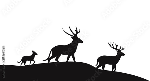 Black deer family silhouette standing on hill.