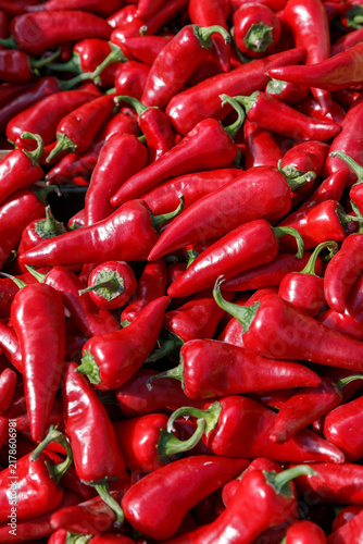 Foto Fresh ripe red hot chili peppers and raw Capsicum annuum harvested for spicy culinary ingredients at an outdoor street market display in natural daylight, vertical shot, Warsaw, Poland