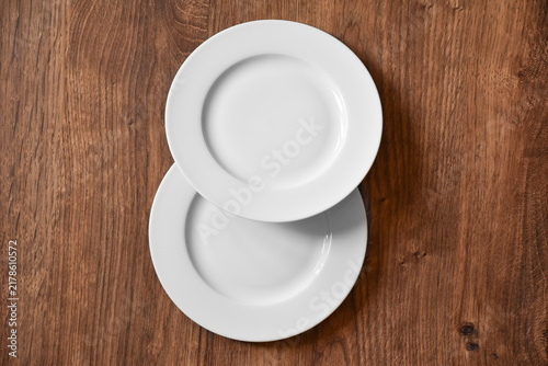 Ceramic white flat plate for food on wooden table top view