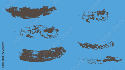 Set of distressed brown ink paint brush strokes and grunge texture elements for artistic design on blue background.