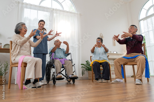 Konstfotografi Caregiver leading senior group exercise with resistance bands in nursing home