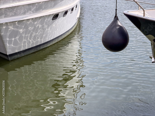 Black Spherical Boat Fender Hanging Between Moored Yachts at Antwerp Marina, Belgium