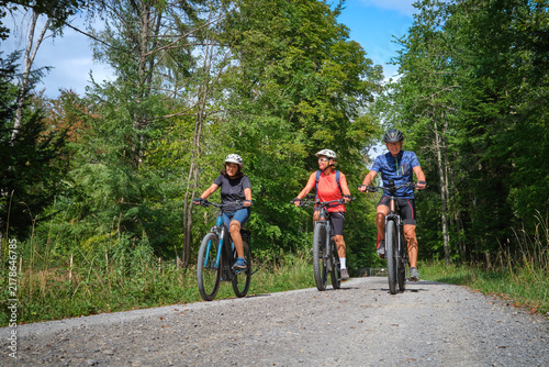 Three senior friends enjoy a cycling tour through a peaceful forest on a sunny day, promoting friendship, fitness and active aging in Naturpark Schönbuch, Herrenberg, Baden-Württemberg, Germany.